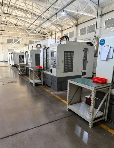A row of industrial CNC machining centers in a modern precision manufacturing facility.